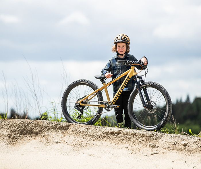 Ein Kind steht hinter seinem Fahrrad in der Natur