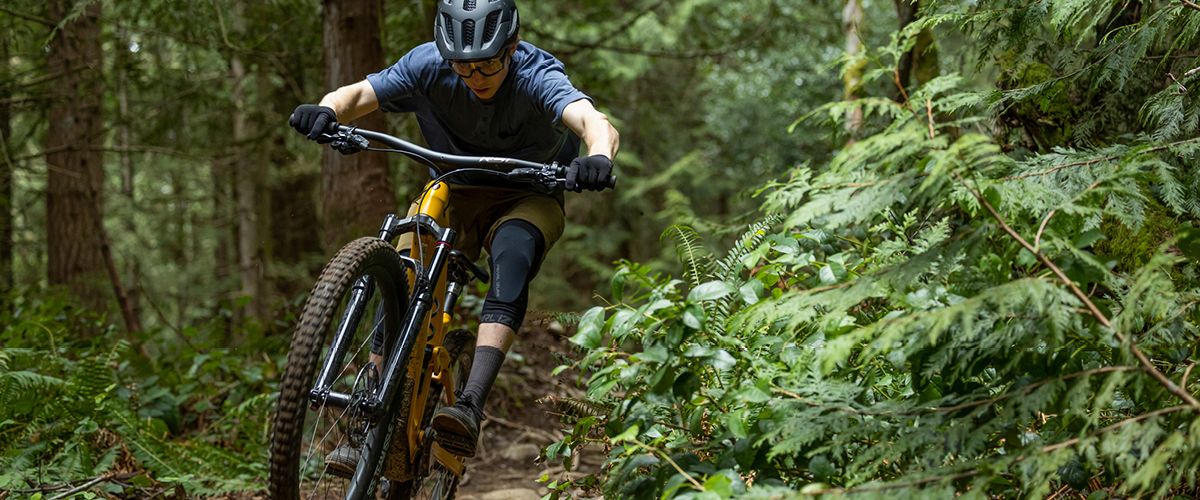 Mountainbiker springt von einem Felsen in einem dichten Wald