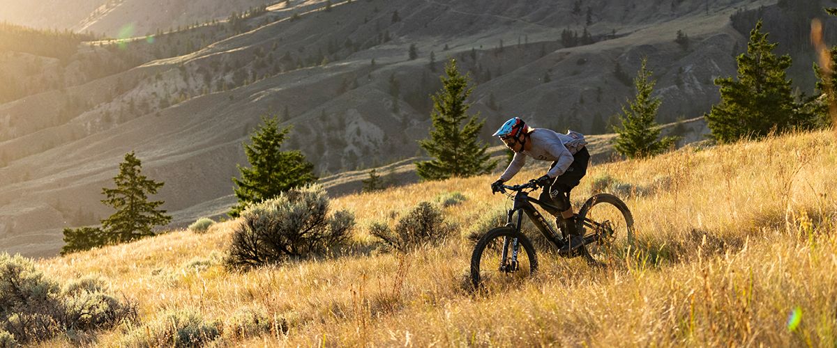 Mountainbikerin mit Helm inmitten einer bergigen Landschaft 