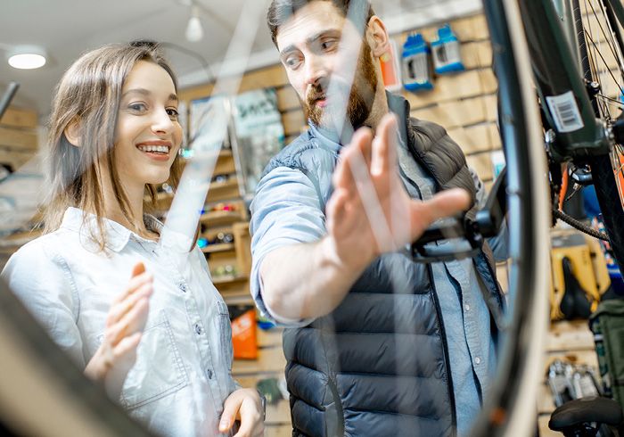 Ein Mann und eine Frau in einem Fahrradgeschäft. Der Mann zeigt auf ein Fahrrad, während die Frau lächelt. 