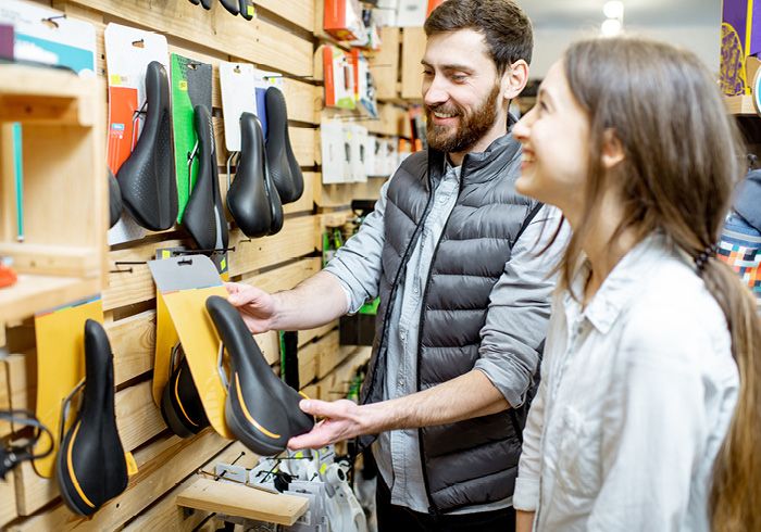 Mann und Frau in einem Fahrradgeschäft betrachten verschiedene Fahrradsättel.