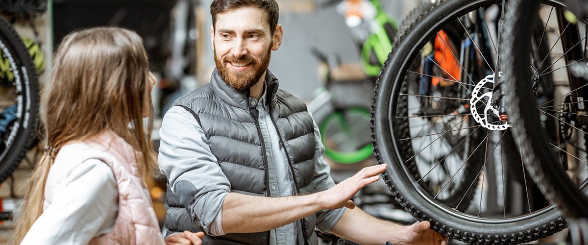 Mann zeigt einer Frau ein Fahrradrad in einem Fahrradgeschäft.