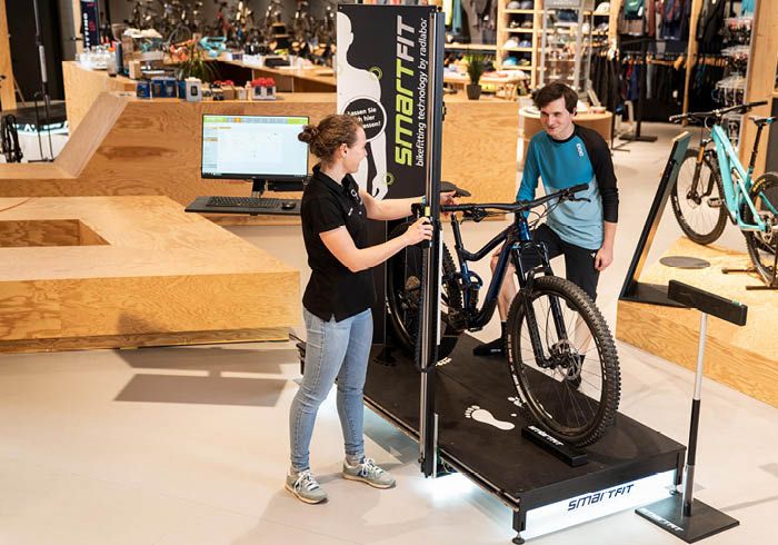 Zwei Personen in einem Fahrradgeschäft verwenden das SmartFit-System zur Vermessung und Anpassung eines Fahrrads.